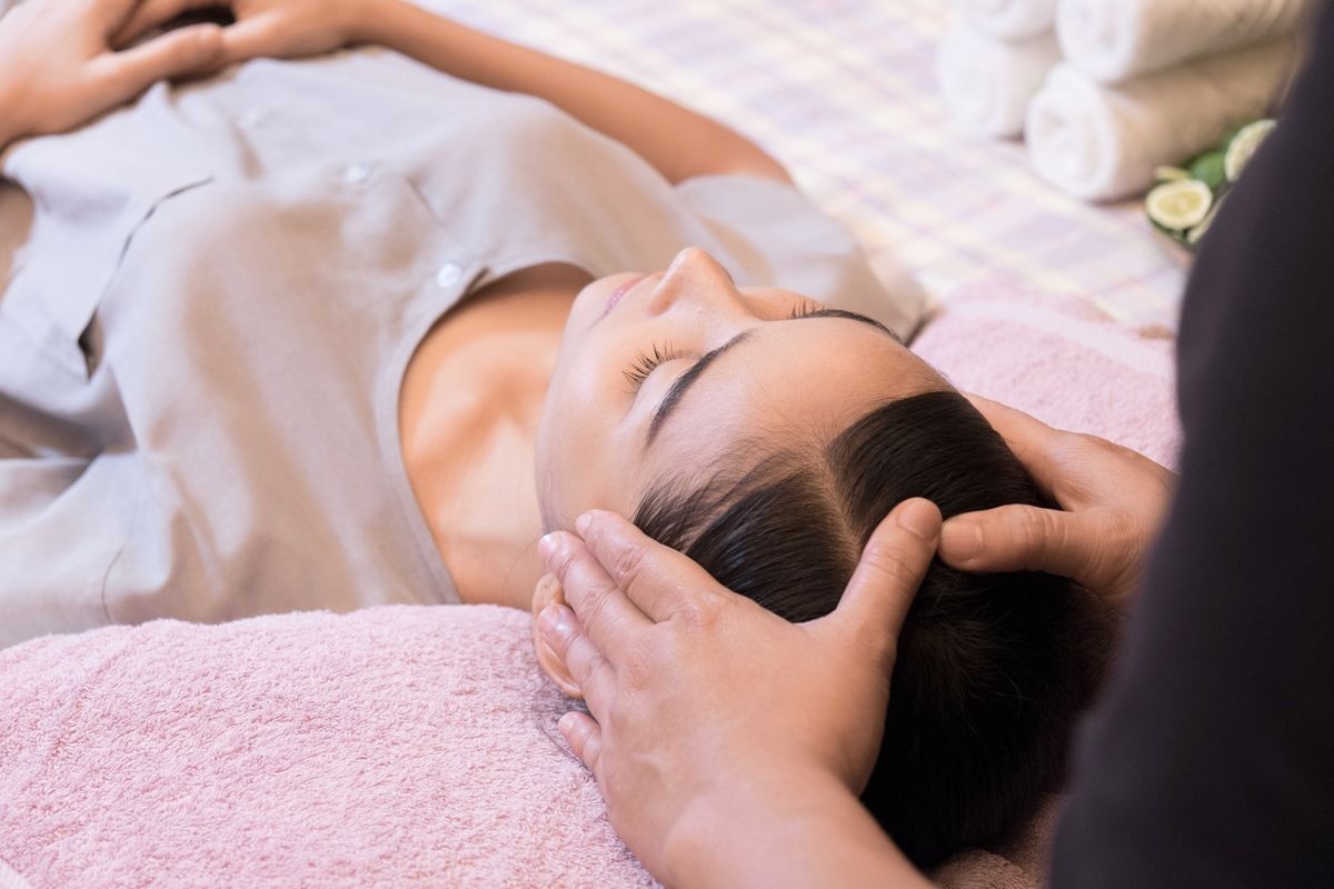 Closeup of a young woman receiving a relaxing head massage in a spa center